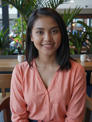 Smiling Bruneian woman in elegant coral blouse at a tropical cafe - Bruneian women dating profile on FloridaDatingService